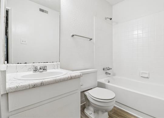 A white bathroom with a marble sink and toilet.