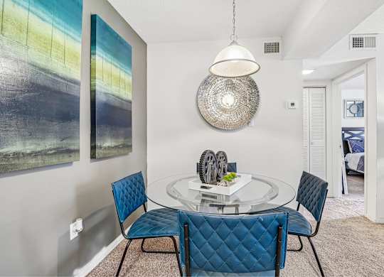 A modern dining room with a glass table and blue chairs.