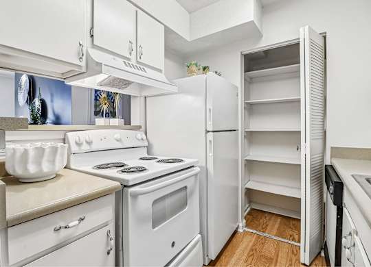 A white kitchen with a stove, oven, and refrigerator.