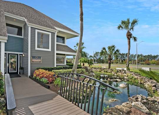 A house with a deck and a pond in front.