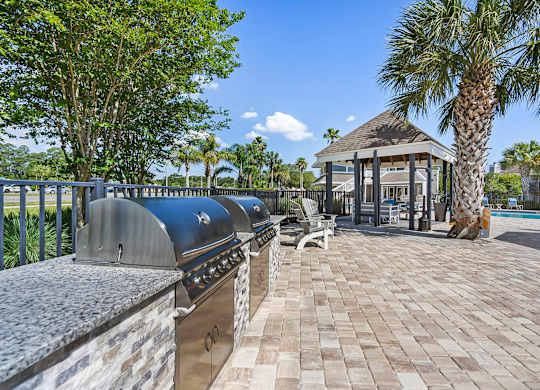 A gazebo is surrounded by a brick walkway and palm trees.