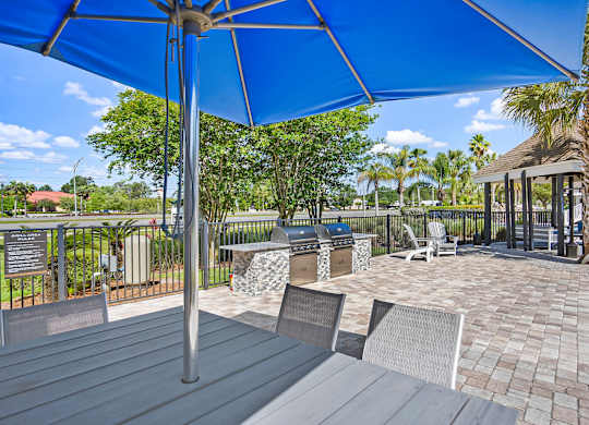 A patio with a blue umbrella and chairs.