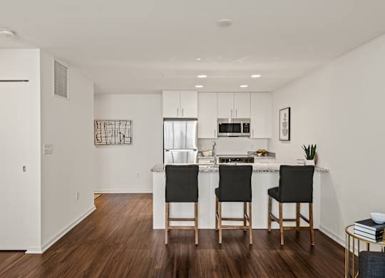 A kitchen with a white countertop and black chairs.