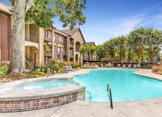 A swimming pool surrounded by a brick wall and trees.
