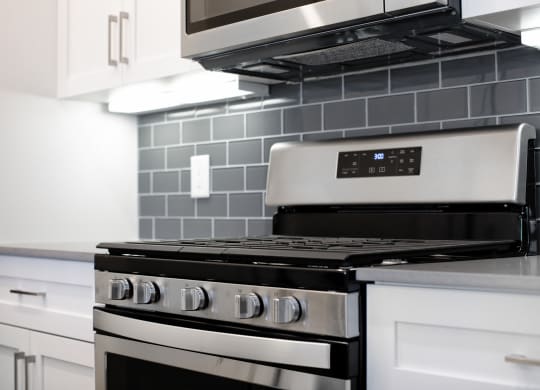 Close up of oven with microwave above and gray tile backsplash
