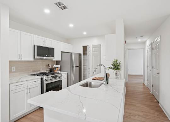 A kitchen with white cabinets and a white countertop.