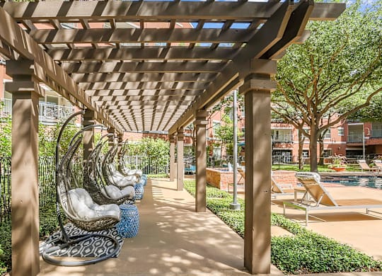 A row of concrete statues are lined up under a wooden pergola.