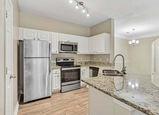 A kitchen with a granite counter top and stainless steel appliances.