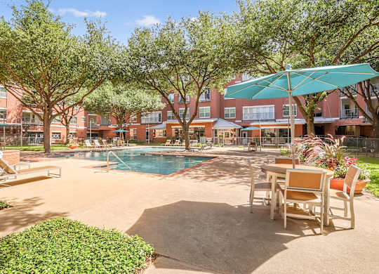 A pool surrounded by chairs and trees.