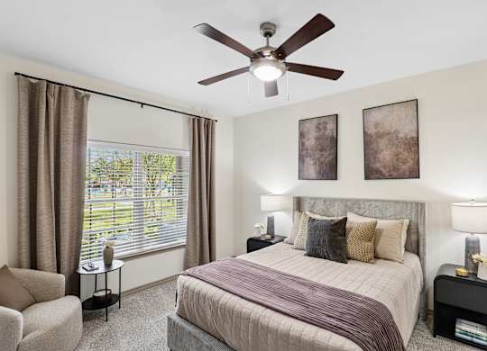 A bedroom with a bed, chair, and window.