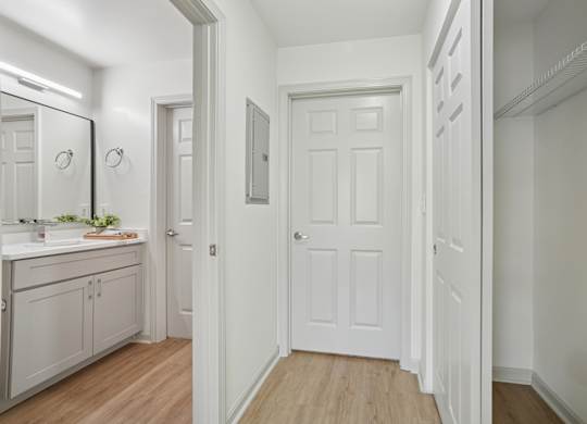 A white door is in a hallway with a mirror on the wall.