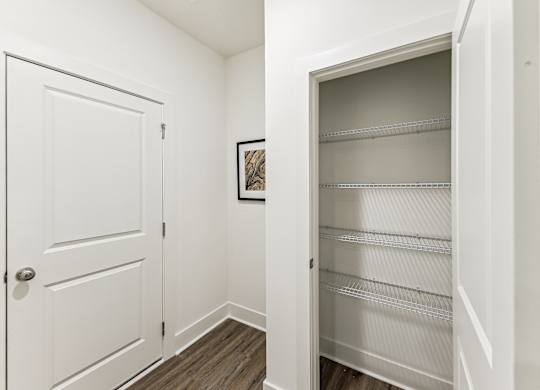 an empty closet with a white door and a door to a white closet with shelves
