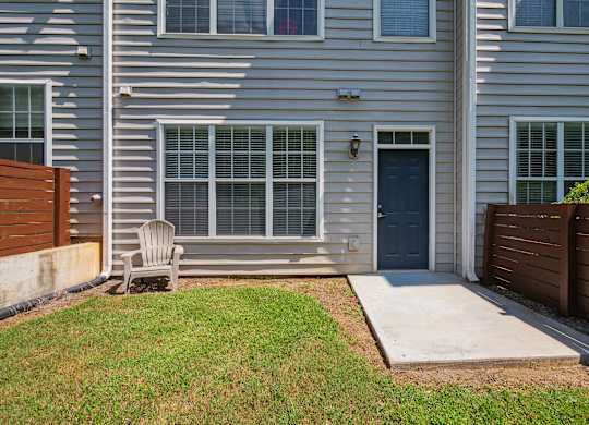 A grey house with a blue door and a wooden fence.