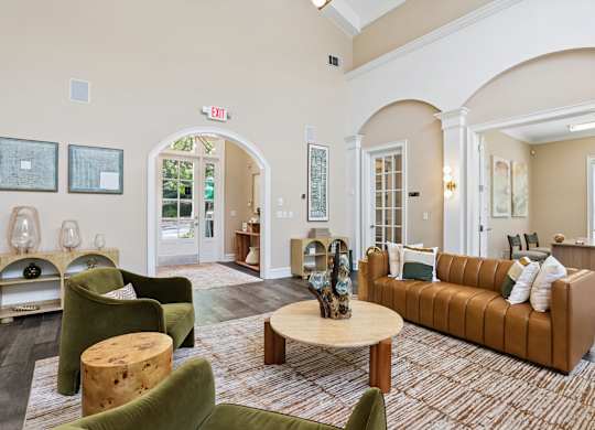 A living room with a brown couch and green chairs.