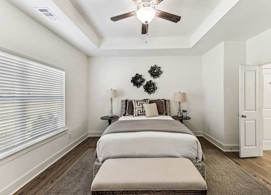 A bedroom with a bed, two lamps, and a ceiling fan.