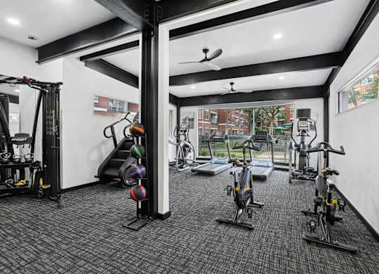 A gym with a variety of exercise equipment including treadmills, stationary bikes, and weight machines.