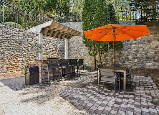 A patio with a table and chairs under an orange umbrella.