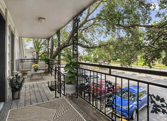 A balcony with a blue car parked on the street.