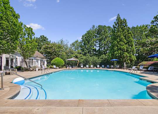 A large swimming pool surrounded by trees and lounge chairs.