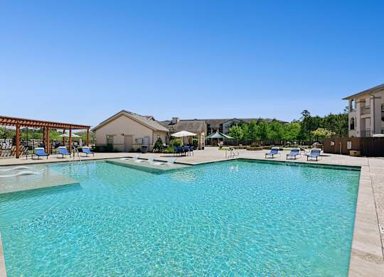 A large swimming pool with a wooden pergola on the left side and gas grill.