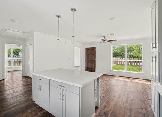 A kitchen with white cabinets and a wooden floor.