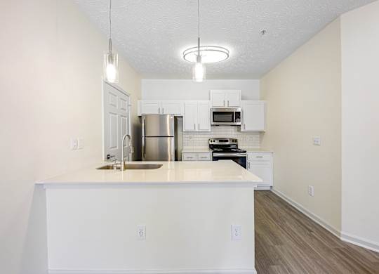 A kitchen with white cabinets and a white island.