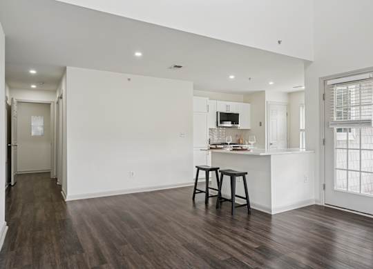 A kitchen with white walls and a wooden floor.