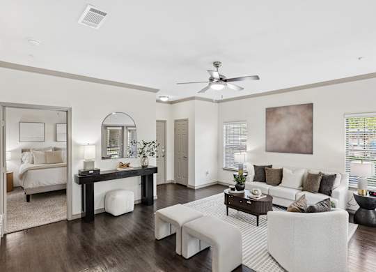 A spacious living room with a white sofa set and a wooden coffee table.