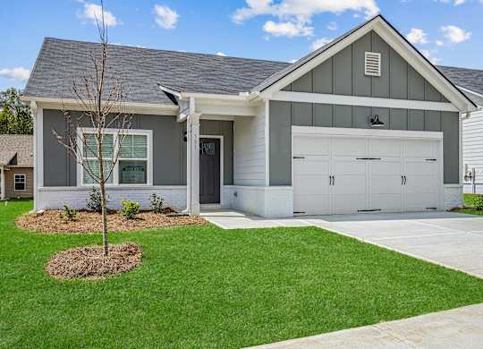 a white and gray house with a garage and a lawn