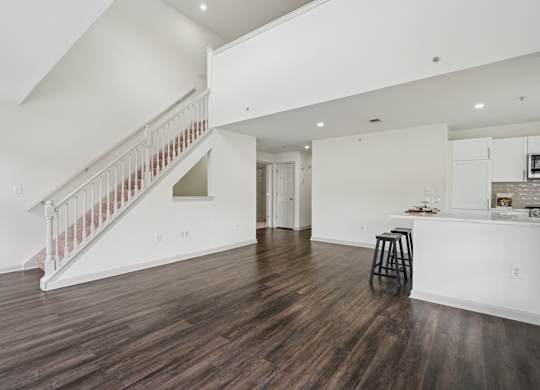 A living room with a bar area and a staircase.