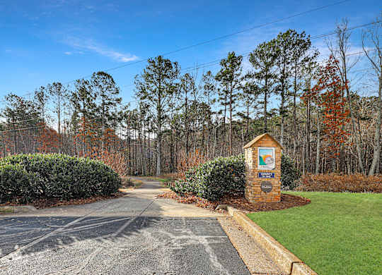 A sign in front of a hedge surrounded by trees.