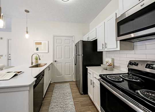 A kitchen with black appliances and white cabinets.