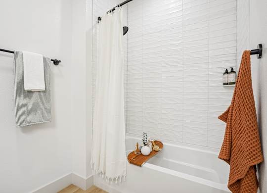 A white bathroom with a white tub and a white shower curtain.