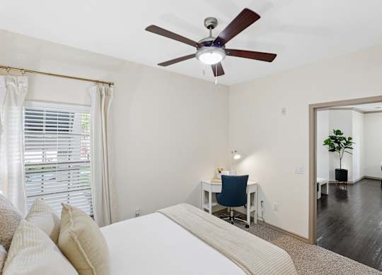 A bedroom with a bed, desk, and chair.
