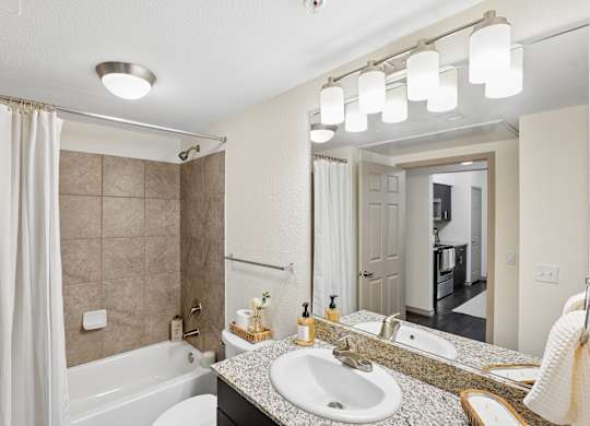 A bathroom with a white tub, sink, and mirror.