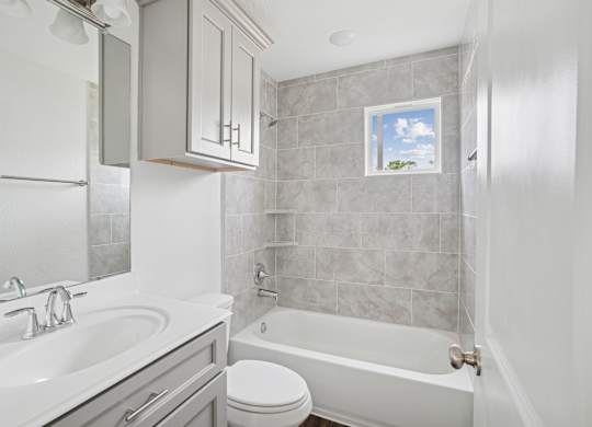 A bathroom with a white tub, sink, and toilet.