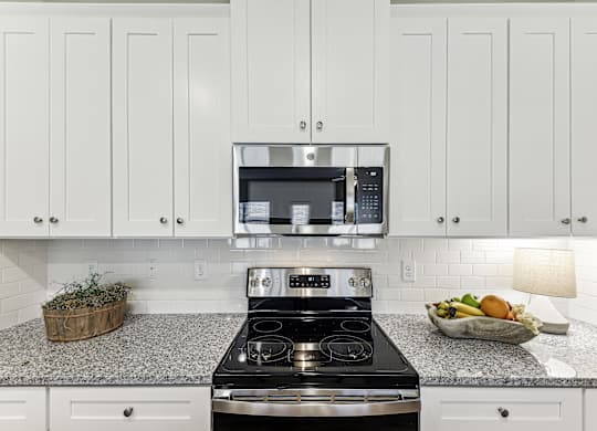 A kitchen with a black stove top oven and a microwave above it.