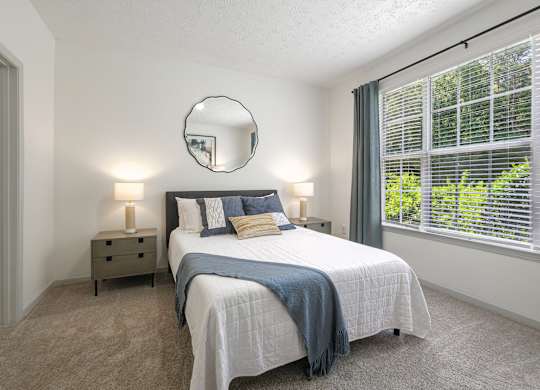 A bedroom with a large bed and a round mirror on the wall.