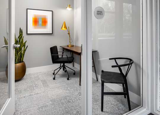 A modern office space with a chair, desk, and a framed picture on the wall.