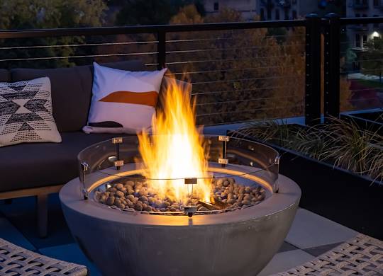 A fire pit with a fire burning in it on a balcony.