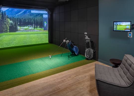 A room with a golf simulator and a chair.