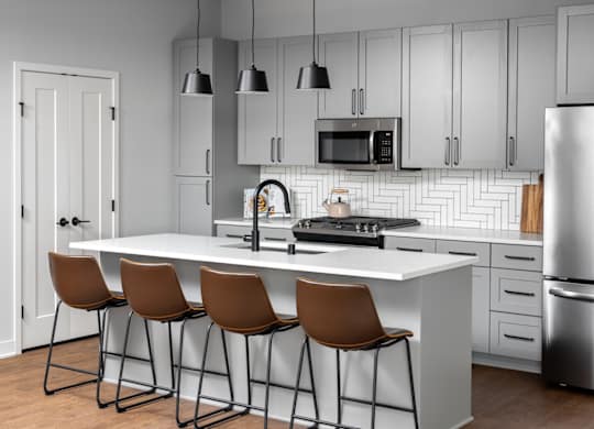 A modern kitchen with a white island and brown barstools.