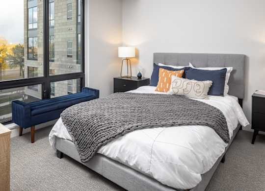 A bedroom with a large bed and a window overlooking a cityscape.