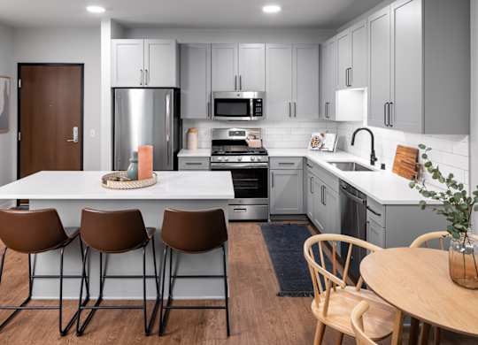 A modern kitchen with a white table and brown chairs.