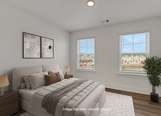 A bedroom with a large bed and a potted plant.