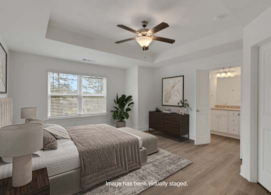 A bedroom with a bed, dresser, and ceiling fan.