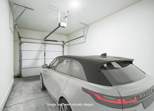 A Range Rover is parked in a garage with a lift above it.