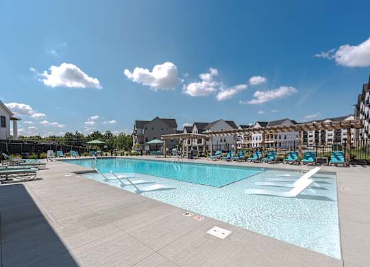 A large swimming pool surrounded by a fence and chairs.