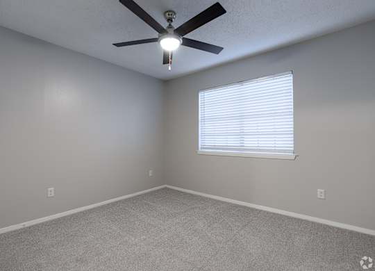 A room with a ceiling fan and a window with blinds.