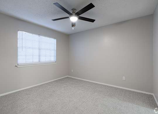 A room with a ceiling fan and a window with blinds.
